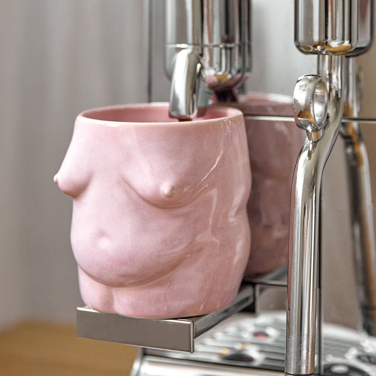handgemachter Body Becher aus Keramik in Rosa unter einer Espressomaschine beim Kaffeebezug