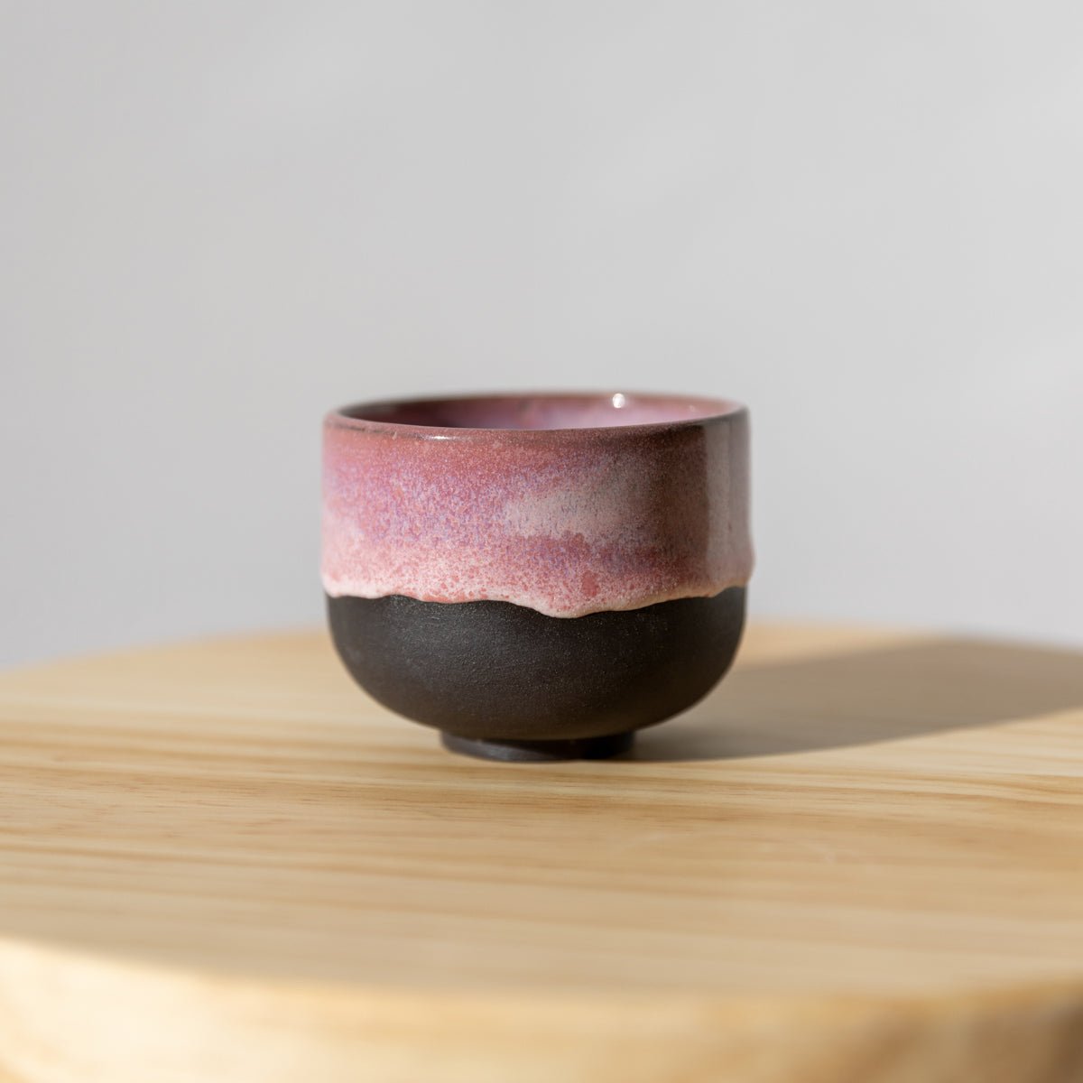 handgefertigter Keramik Cup in Rosa und Dunkel von Studio Amun auf Holzoberfläche