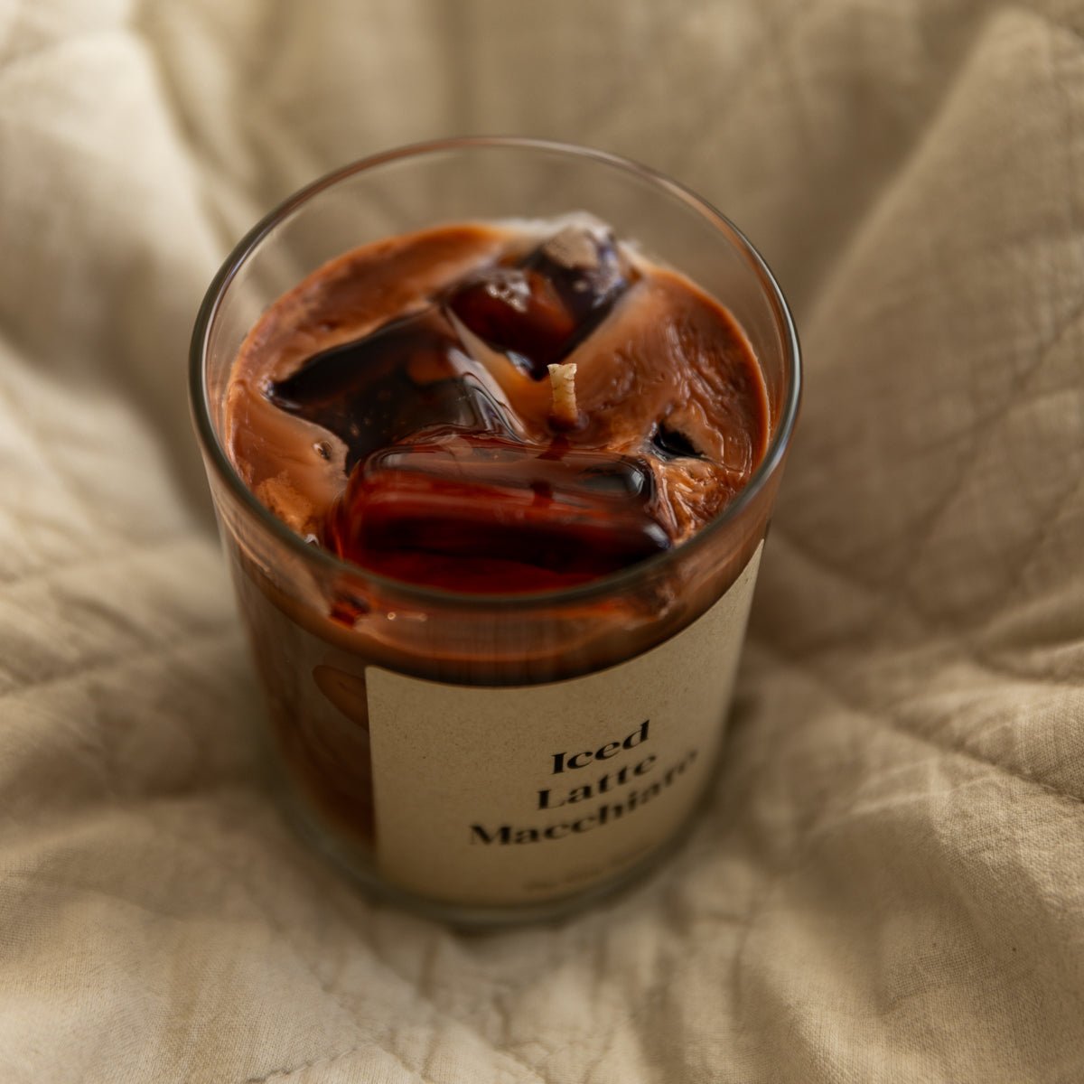 handgegossene Duftkerze mit warmem Duft im Glas auf Bettdecke von Studio Amun 