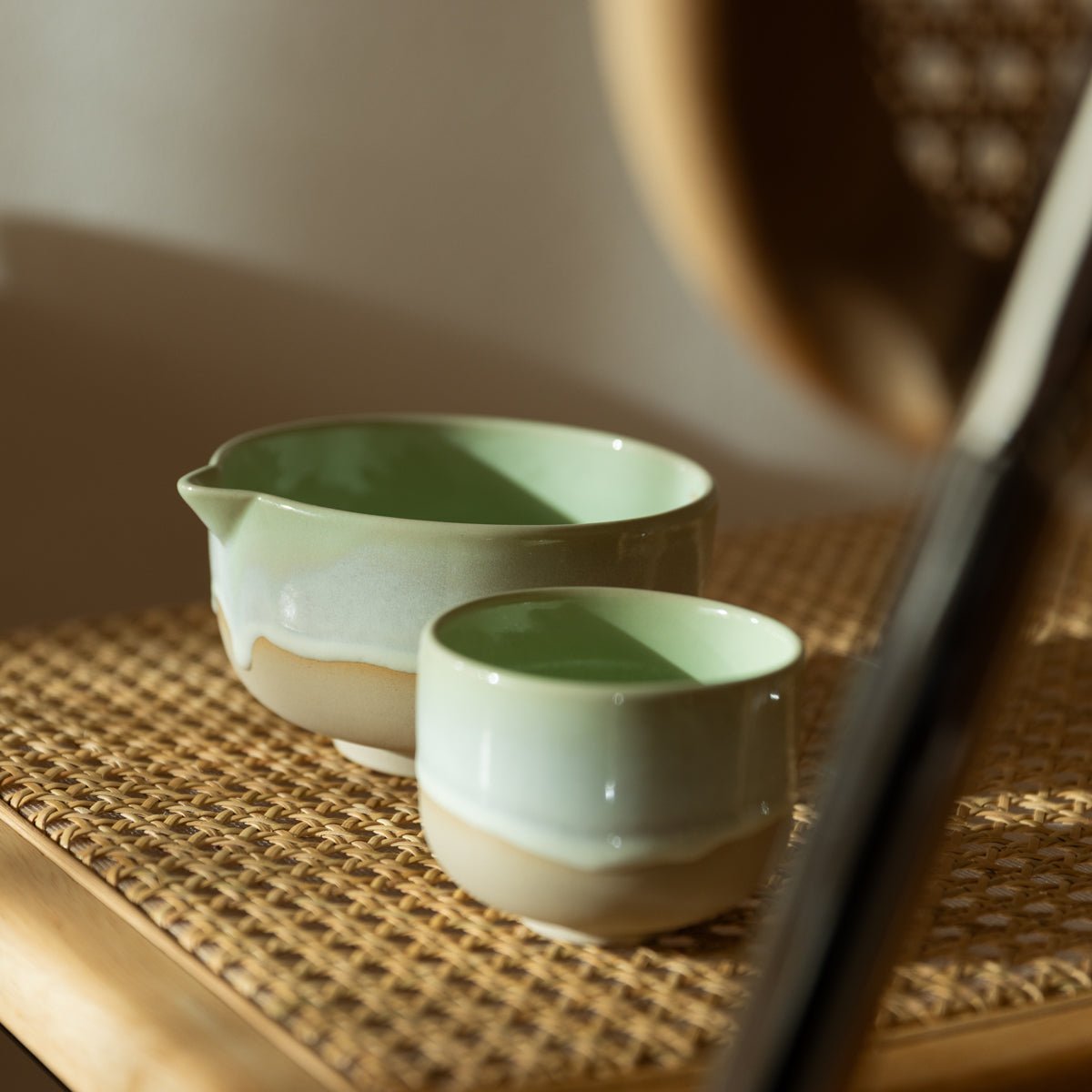handgefertigte Keramik Cups in Grün von Studio Amun auf geflochtener Unterlage