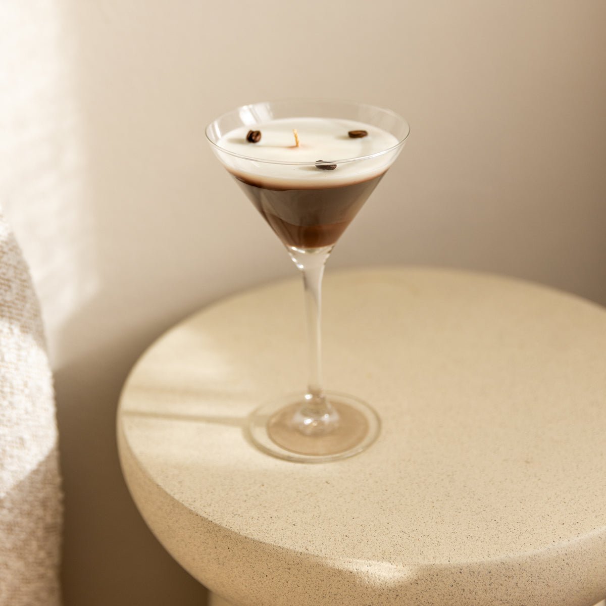 handgegossene Duftkerze im Cocktailglas von Studio Amun auf rundem Tisch in warmem Licht