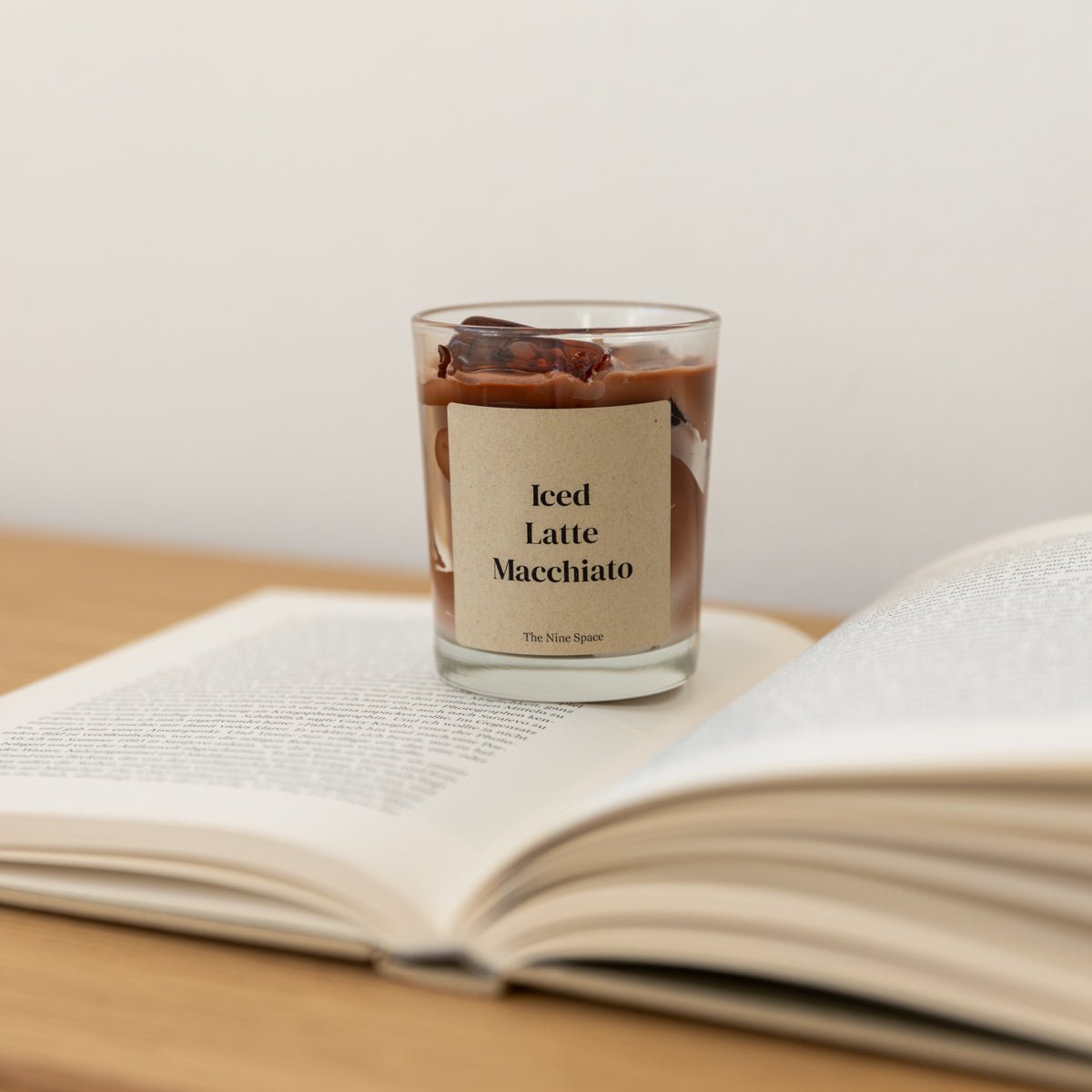 handgegossene Duftkerze im Glas im Iced Latte Macciato Look von Studio Amun auf einem offenen Buch in ruhiger Atmosphäre